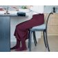 Kobieta siedzi przy stole na niebieskiej poduszce klinowej, wspierającej ergonomiczną pozycję.